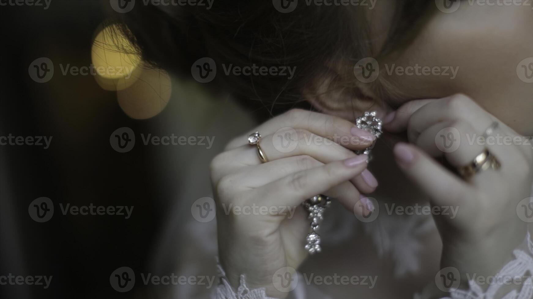 Beautiful bride in puts on earring. Beauty model girl is wearing jewelry for marriage. Wedding female portrait. Woman with curly hair and lace veil. jewelry and beauty concept - close up of wearing photo