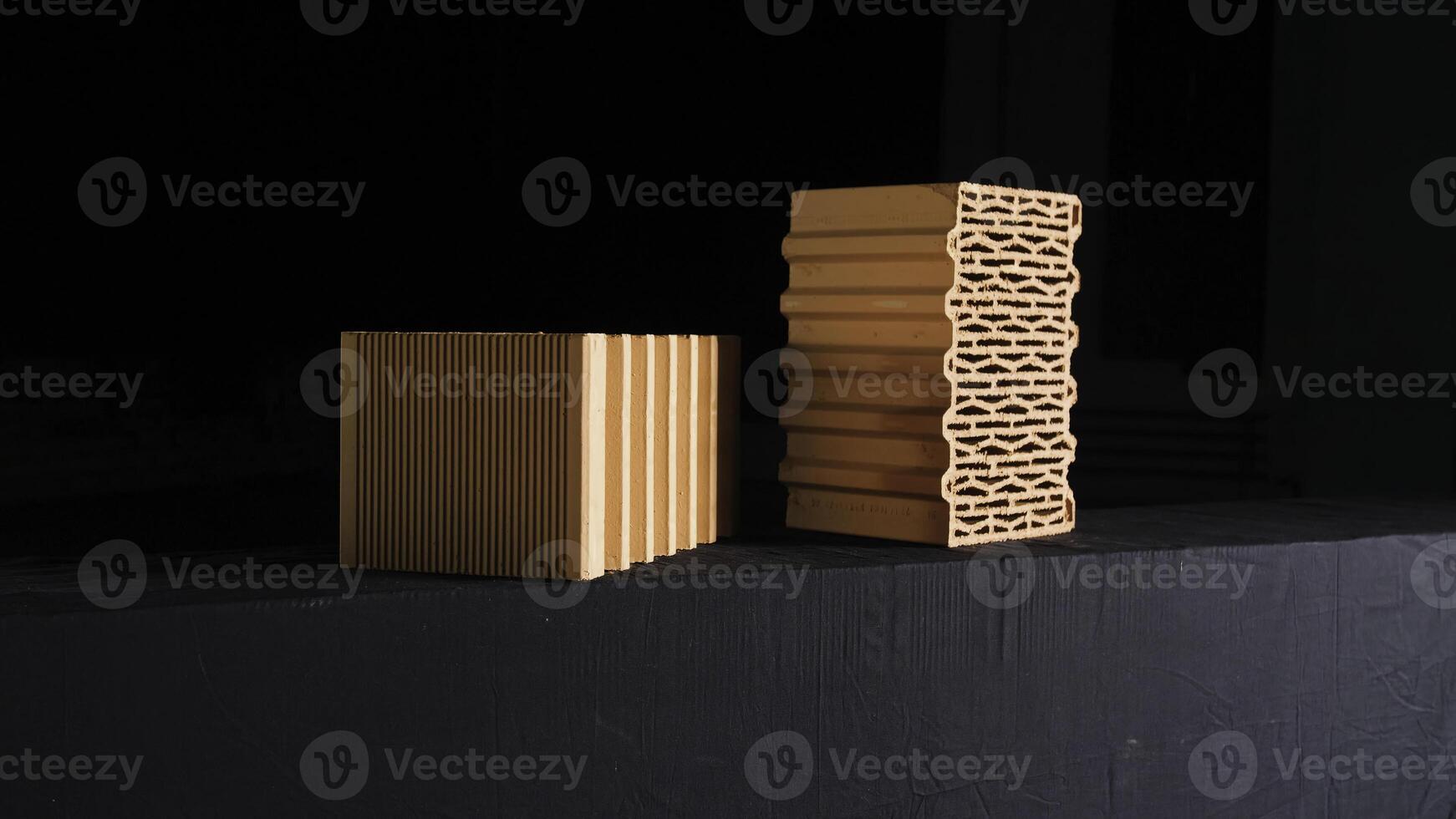 Close-up of two red bricks on black background. Stock footage. Demonstration of two red ceramic blocks with wavy lines for building house on black background photo