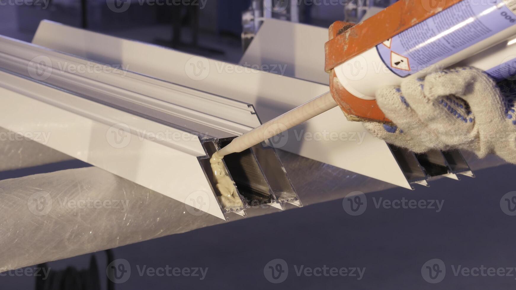 Hands of worker using a silicone tube for repairing of window indoor. Window details from aluminum. Construction worker installing window in workplace. Backview of old man using a silicone tube for photo