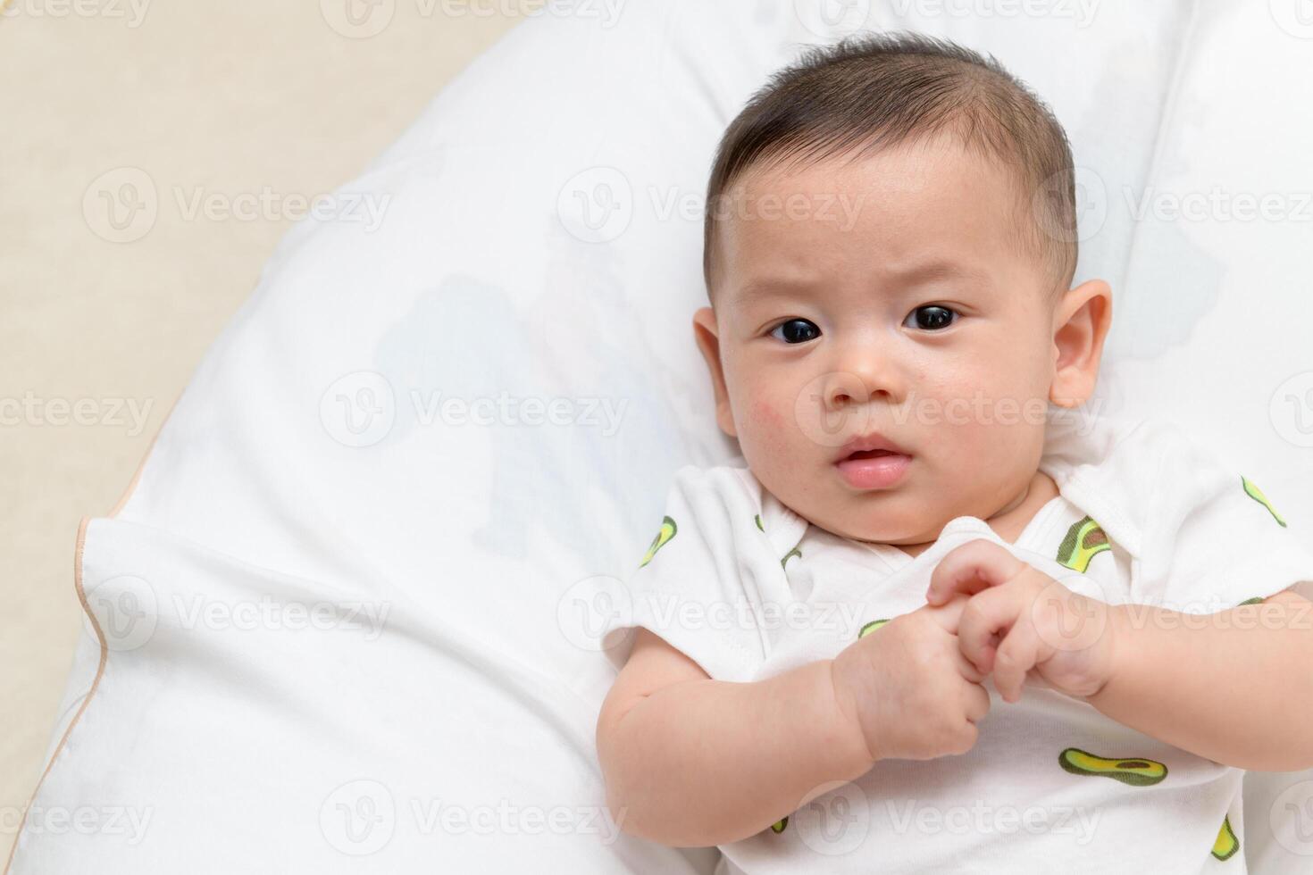 happy baby boy lying on white bed and look at camera. health care infant photo