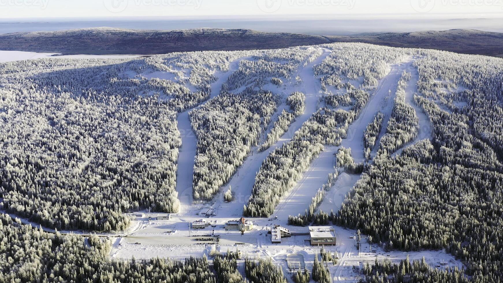 Aerial of the ski resort with funicular in the snowy forest in a sunny day. Footage. Winter landscape of snowy mountain slope among pine trees on blue sky background. photo