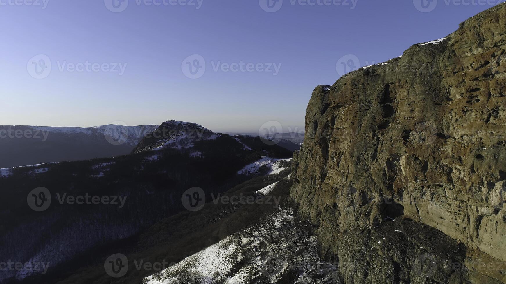 Autumn morning in the mountain, yellow grass, sometimes there is snow and growing coniferous forest. Shot. Aerial of snowy rocks and the endless plain far in the distance. photo