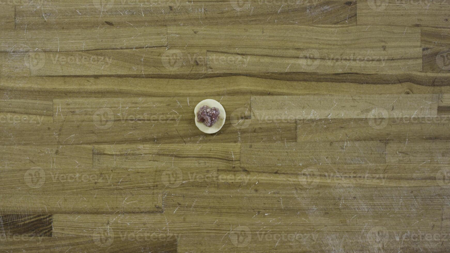 Top view on male hands making dumplings, Man makes dough and meat of dumplings. Cooking at home, hands make meat dumplings on a wooden table. Dumplings, flour, leeks, rolling pin, on wooden table. photo