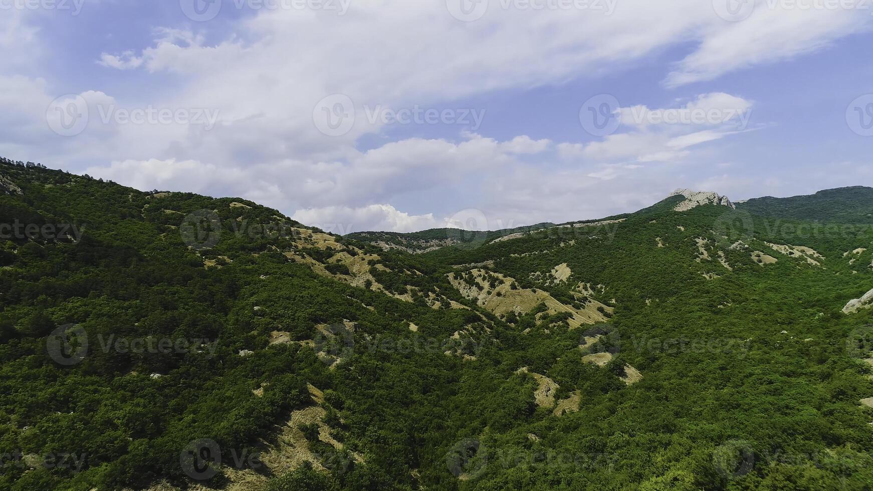 Top view of steep rocky slopes at top of green mountain on background of sky. Shot. Beautiful rocky top of picturesque green mountains photo