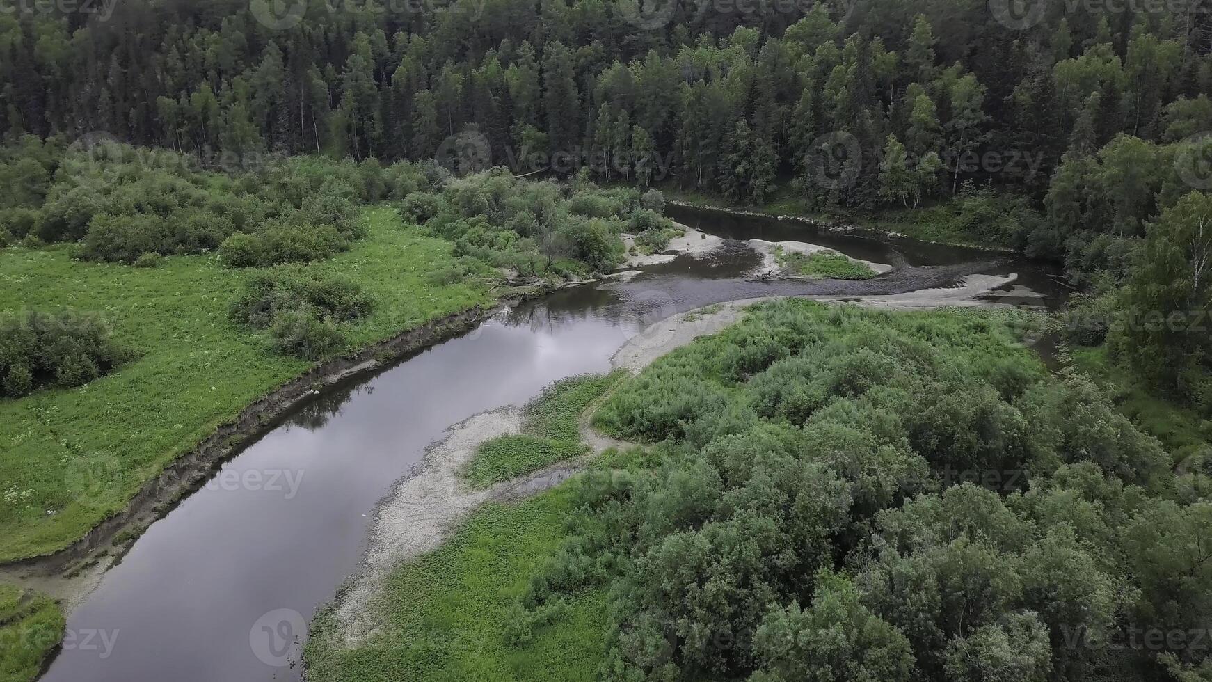Top view of panorama of river passing through forest. Stock footage. Beautiful view of river reflecting sky and surrounding forest photo
