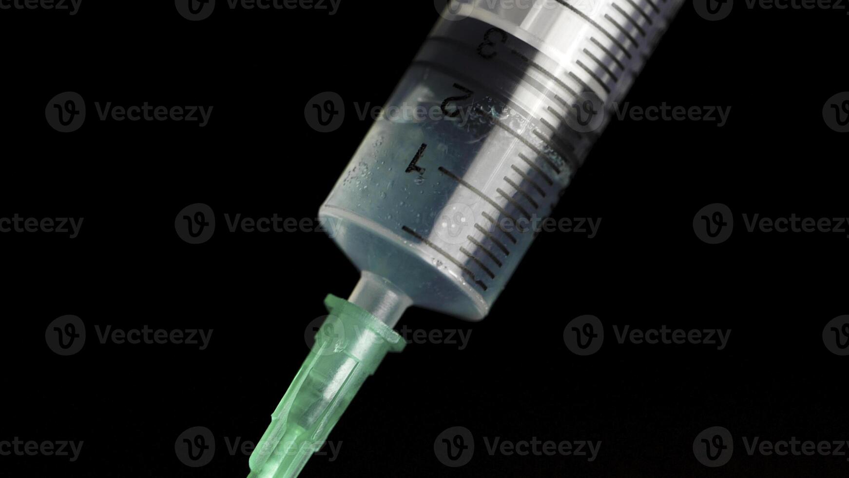 Taking vaccine into a glass syringe from a ampule on a black background. Closeup. Syringe is typed in turquoise fluid injection from illness serious illnesses, the concept of medicine photo