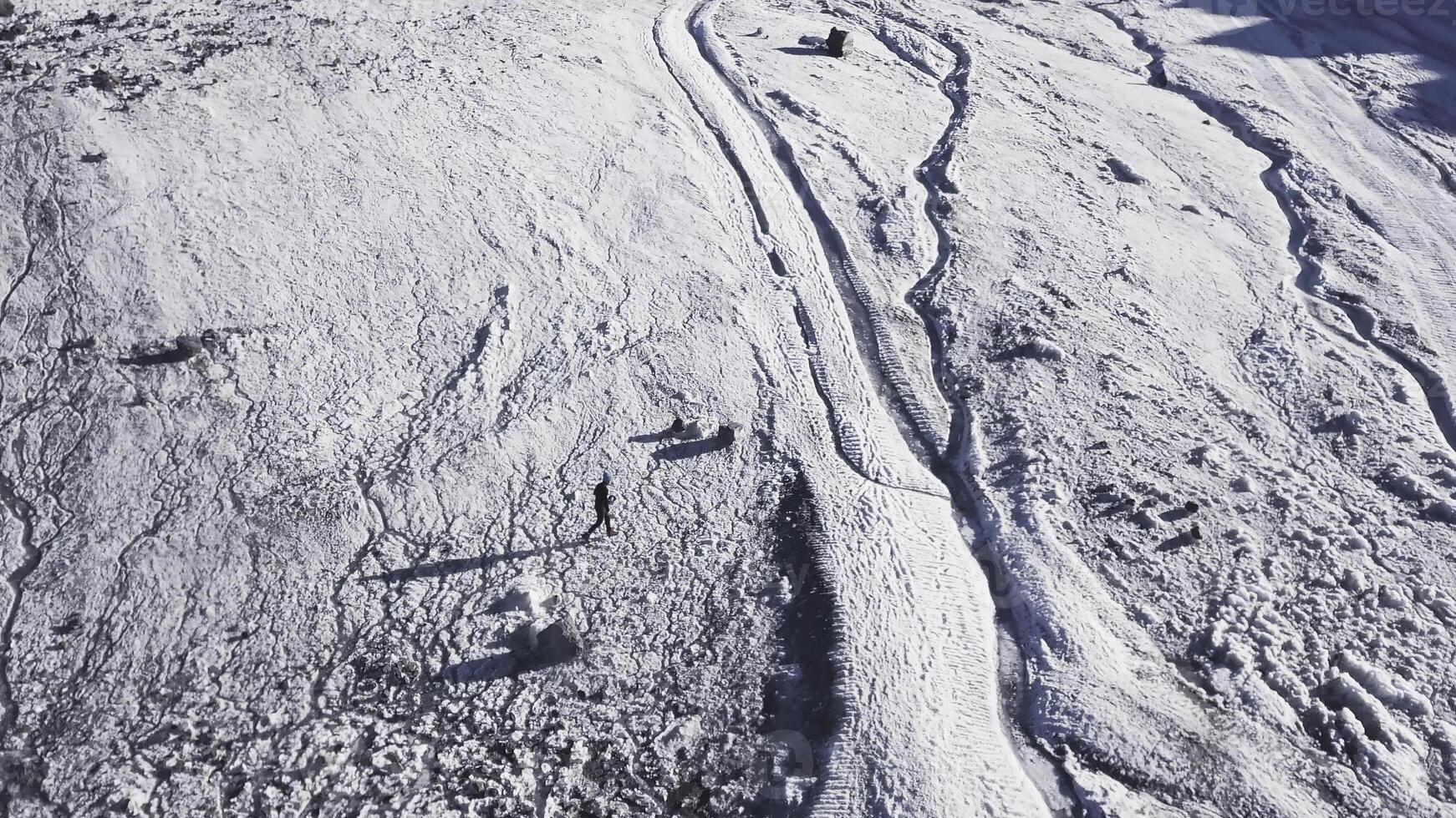 Top view of mountaineer resting in snowy mountains. Clip. Active traveler rests high in snowy mountains. Spectacular views for mountain climbers relaxing on sunny day in mountains photo