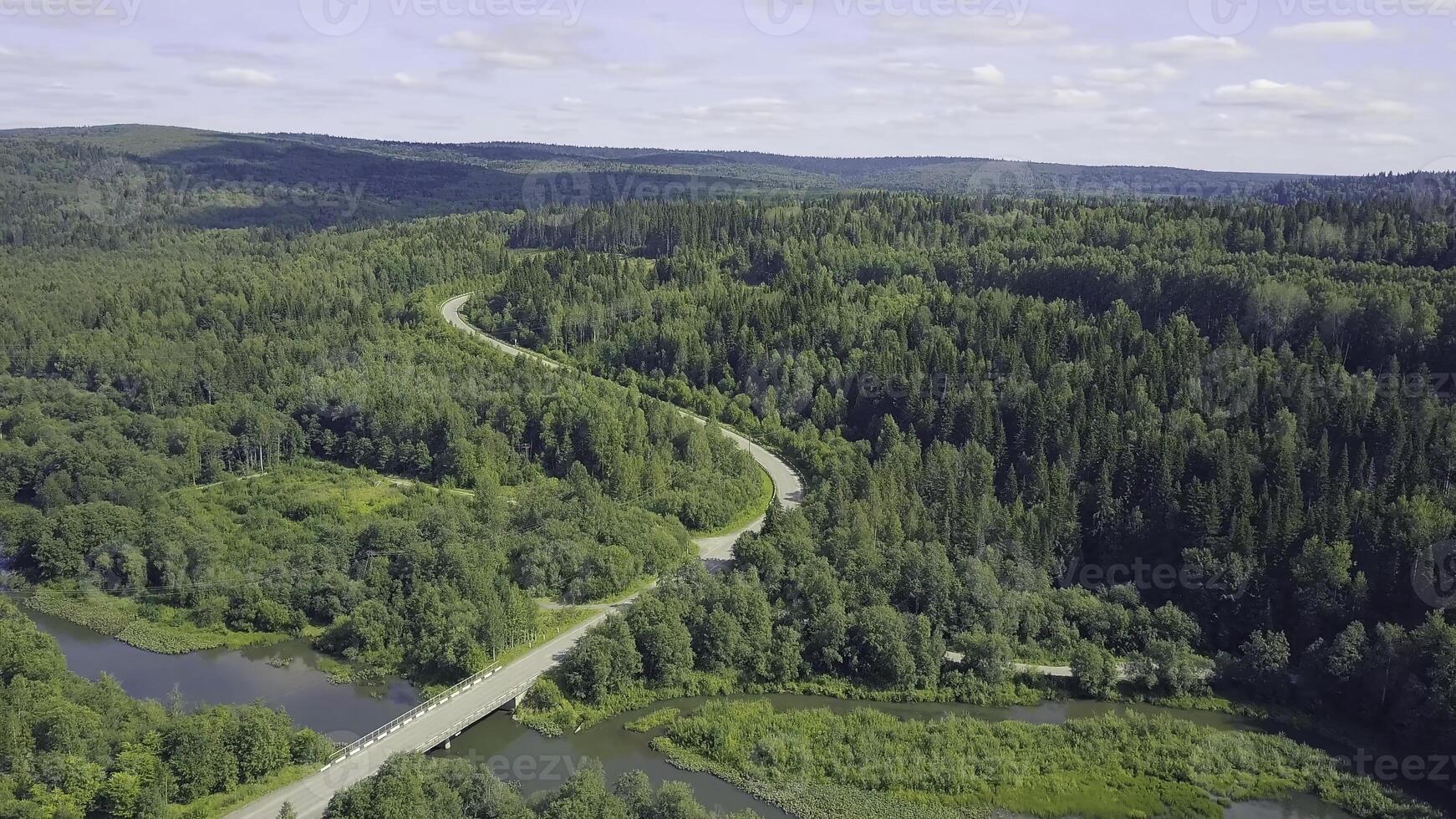 Aerial view of a road in autumn surrounded by pine tree forest. Clip. Top view of the road in the forest photo