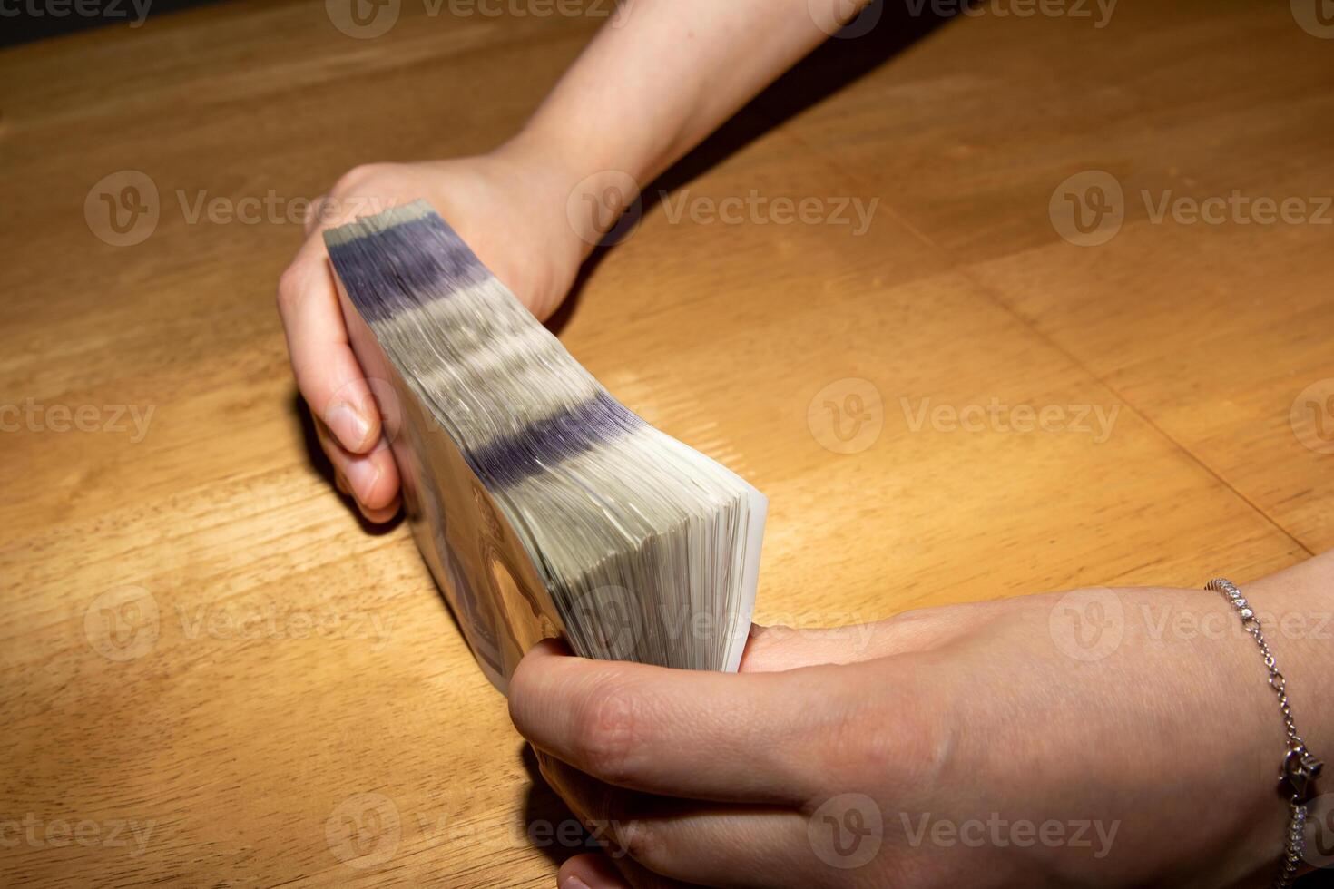A person holding a stack of money on a table photo