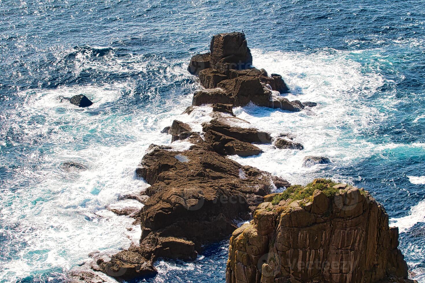 Aerial View of Rocky Coastline with Crashing Waves at Land's End in Cornwall, UK photo