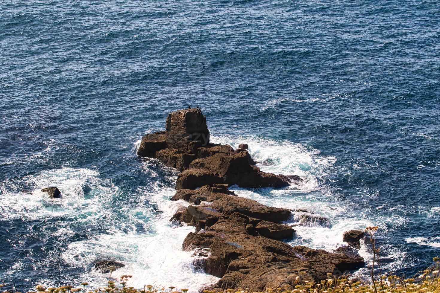 Rocky Outcrop in Deep Blue Ocean at Land's End in Cornwall, UK photo