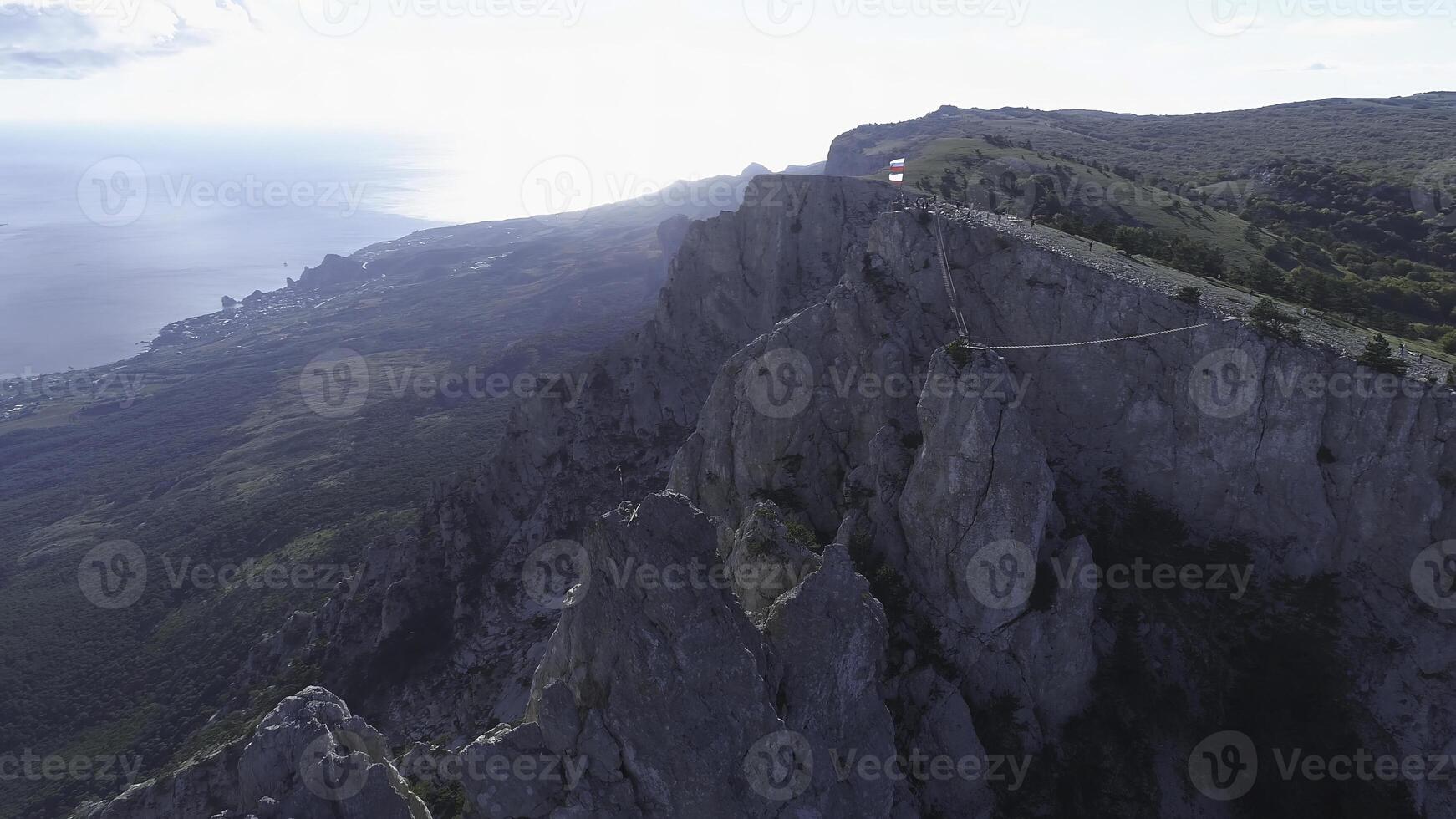 Aerial view of gorgeous white cliff and people standing with flags on the top against blue sky and sea in bright summer day. Shot. Beautiful view from above photo