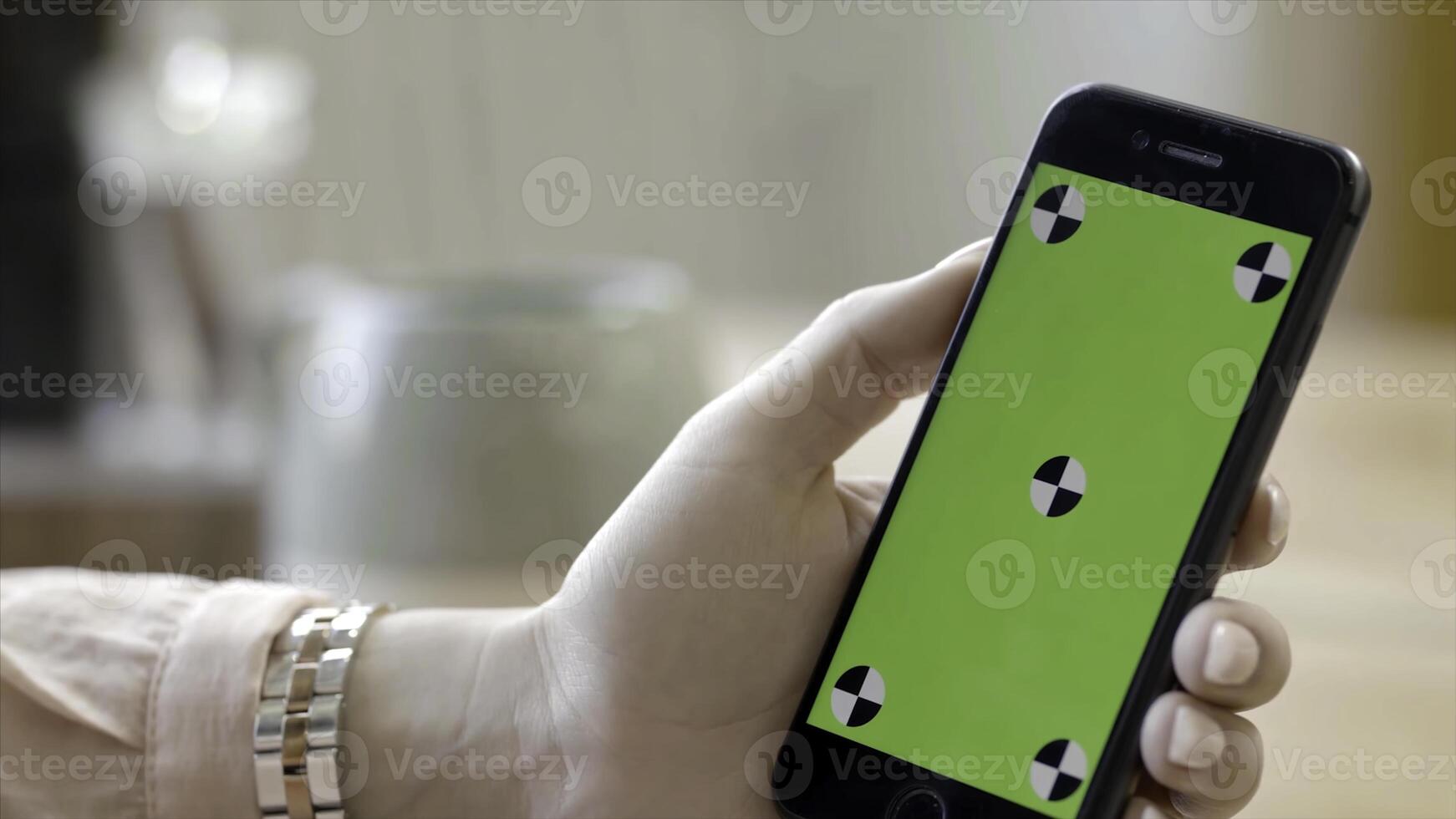 Close-up of woman holding phone with green screen. Stock footage. Beautiful female hand holding phone vertically with green screen. Watch videos on your phone photo