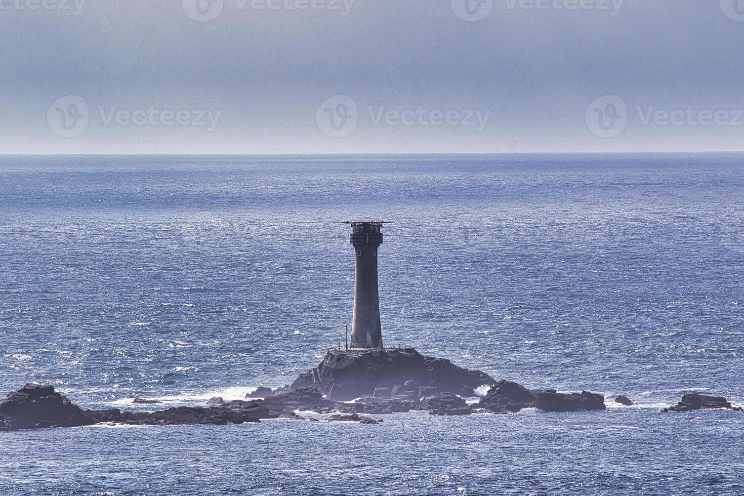 Solitary Lighthouse on Rocky Outcrop at Land's End in Cornwall, UK photo