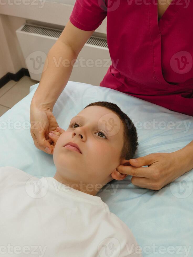 Osteopathy Treatment. Boy's ears being manipulated by real osteopathic physician. Naturopath treats kid with osteopathy as alternative medicine and therapy. Osteopath harmonizes body photo