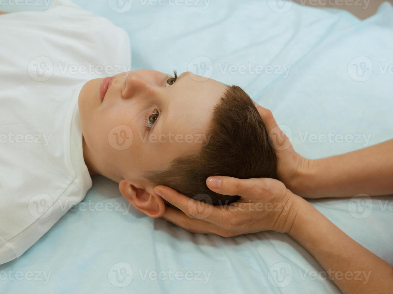 Osteopathy Treatment. Boy's head being manipulated by real osteopathic physician. Naturopath treats kid with osteopathy as alternative medicine and therapy. Osteopath harmonizes body photo