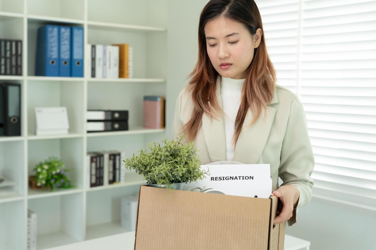 Stressful business women will resign from the company. He is lifting a brown paper box that holds personal items. resignation, job placement and vacancies concept photo
