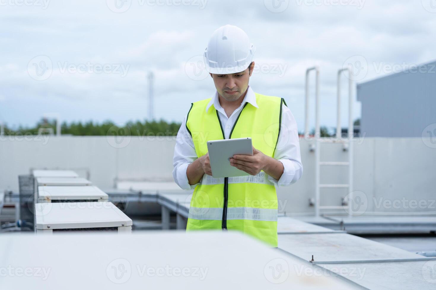 Asian maintenance engineer works on the roof of factory. contractor inspect compressor system and plans installation of air condition systems in construction. technology, online, mobile application. photo