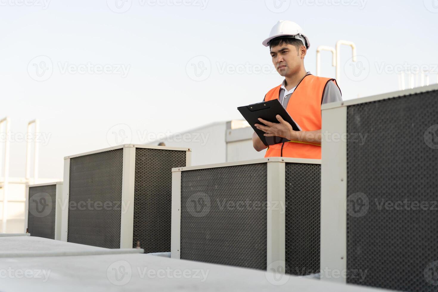 Asian maintenance engineer works on the roof of factory. contractor inspect compressor system and plans installation of air condition systems in construction. Checklist, inspector, control photo