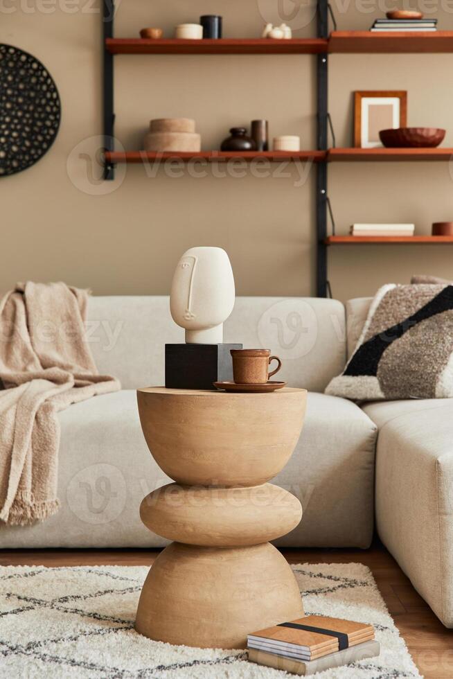 Stylish interior of living room with design rustic coffee table, beige sofa, cup of coffee, book, decoration and elegant accessories in home decor. Template. photo