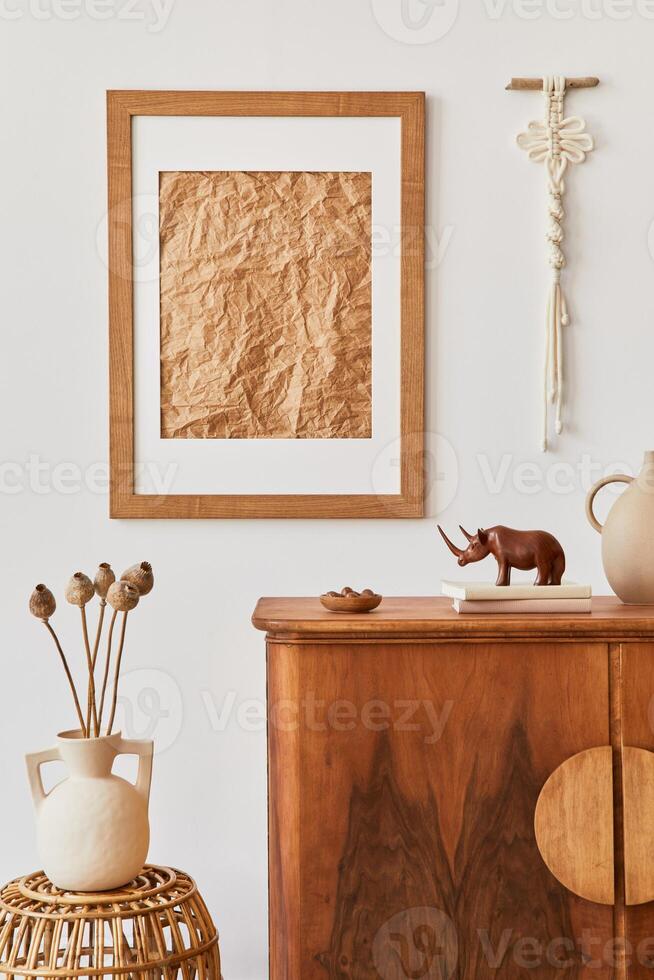 Minimalist composition of living room with brown mock up picture frame, plant, retro commode, decoration and elegant personal accessories in home decor. Template. photo