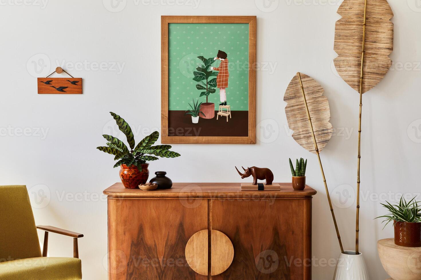 Minimalist composition of living room with brown mock up picture frame, retro armchair, dried tropical leaf, decoration and elegant personal accessories in stylish home decor. Template. photo