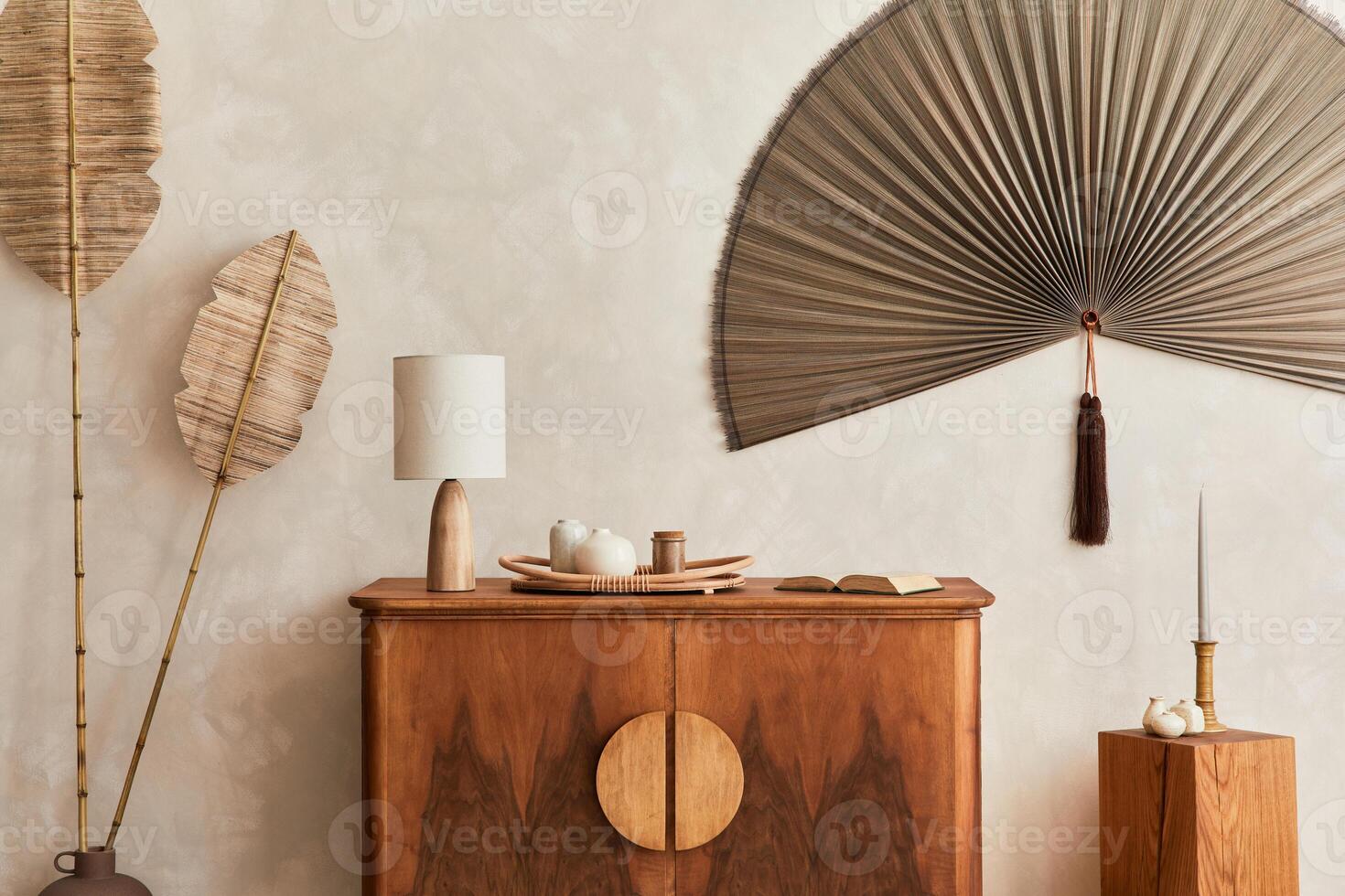Japandi concept of living room with design wooden commode, table lamp, tropical dried leaf in vase, cubes, decoration, japanese fan and elegant personal accessories in home decor. Template. photo
