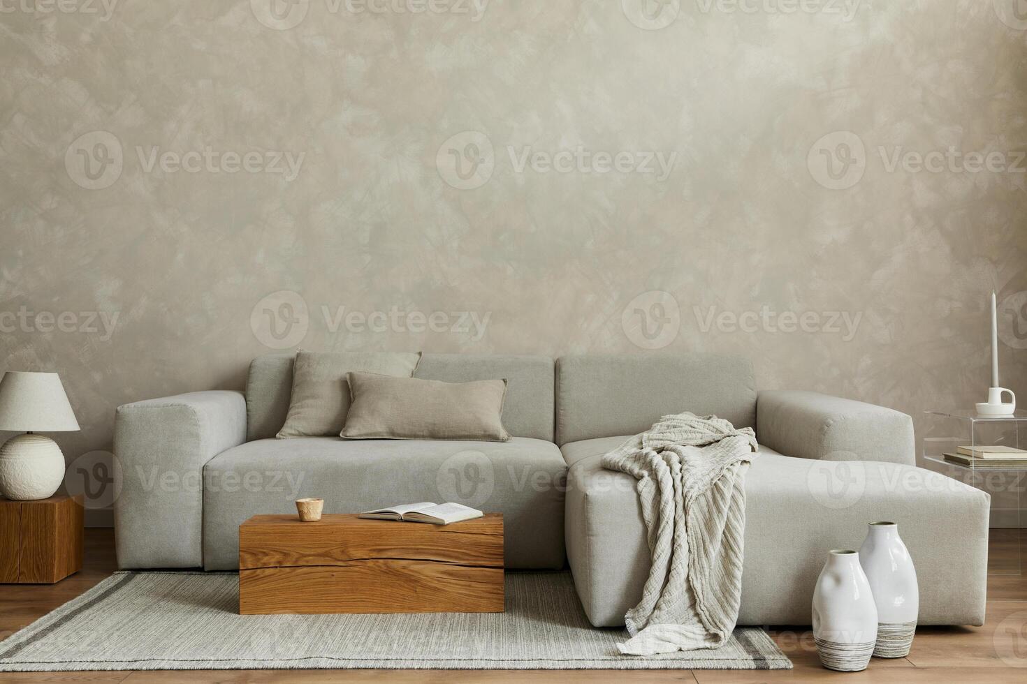 Creative composition of stylish modern spacious living room with grey sofa, pillows, plaid, carpet, white vases and small personal accesories. Creative wall and parquet floor. Template. photo