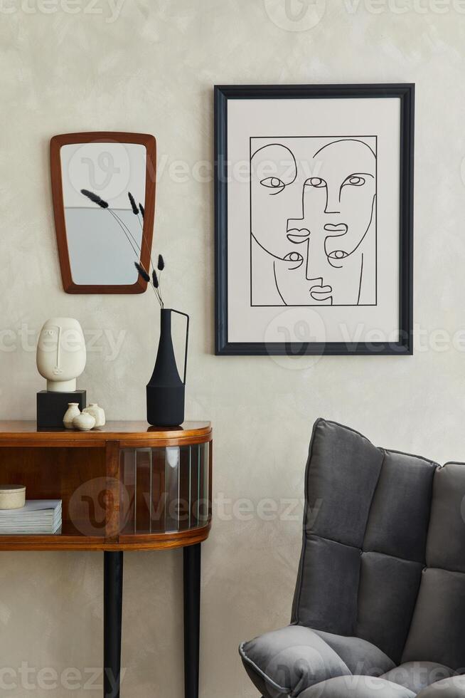Stylish composition of creative living room interior with mock up poster frame, mirror, wooden commode, grey chair and elegant personal accessories. Neutral beige wall. Template. photo