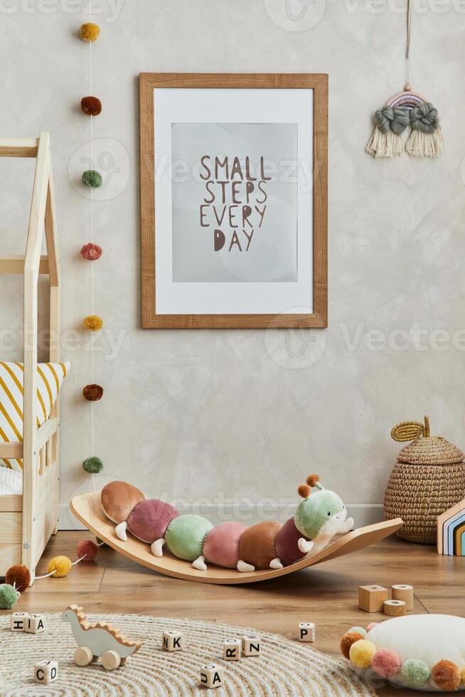 Creative composition of cozy scandinavian child's room interior with mock up poster frame, balance board, plush toys and textile hanging decorations. Creative wall, carpet on the floor. Template. photo