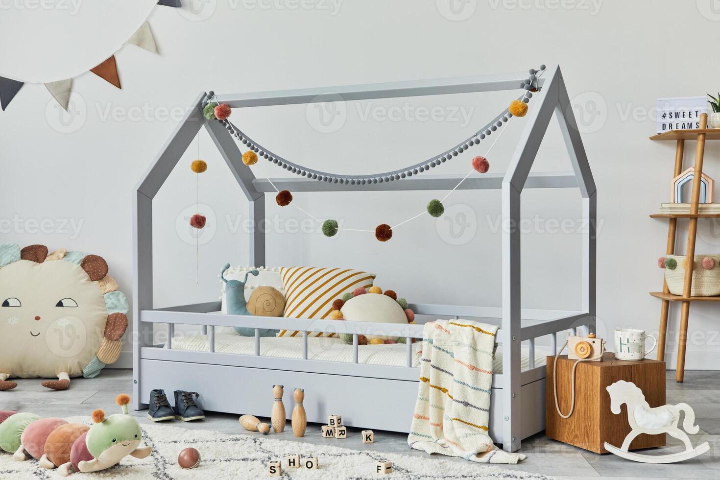 Stylish scandinavian child's room with creative wooden bed, wooden cube, plush and wooden toys and hanging textile decorations. Grey walls, carpet on the floor. Template. photo