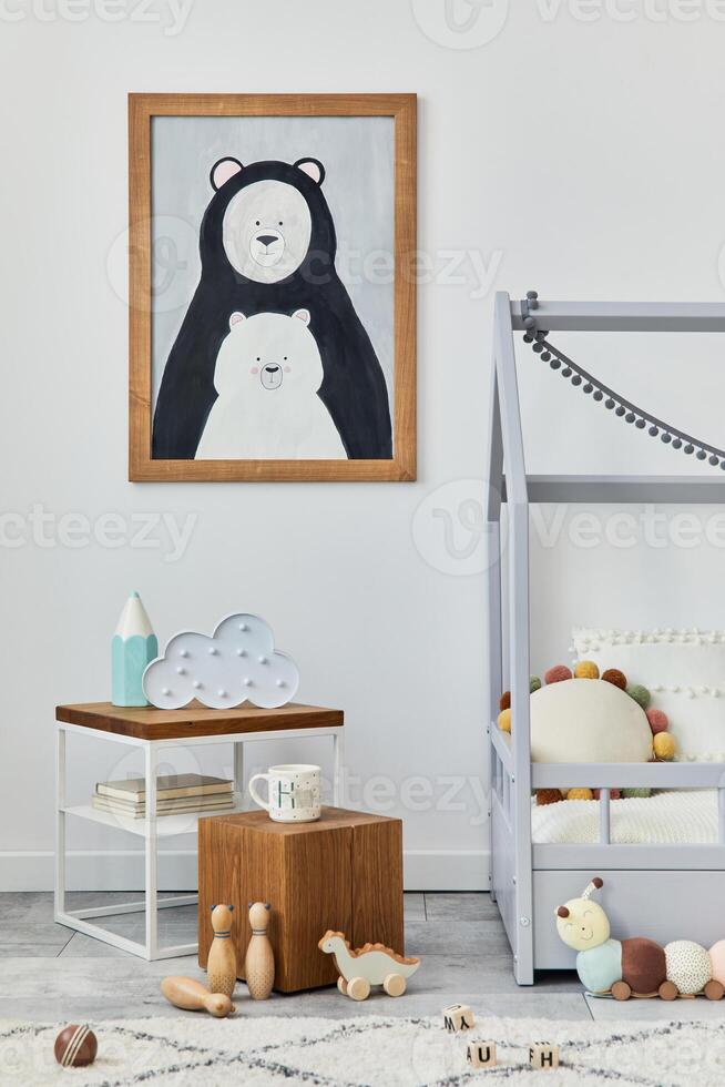 Stylish scandinavian child's room interior with mock up poster frame, creative bed, wooden cube, plush and wooden toys and hanging textile decorations. Grey wall, carpet on the floor. Template. photo