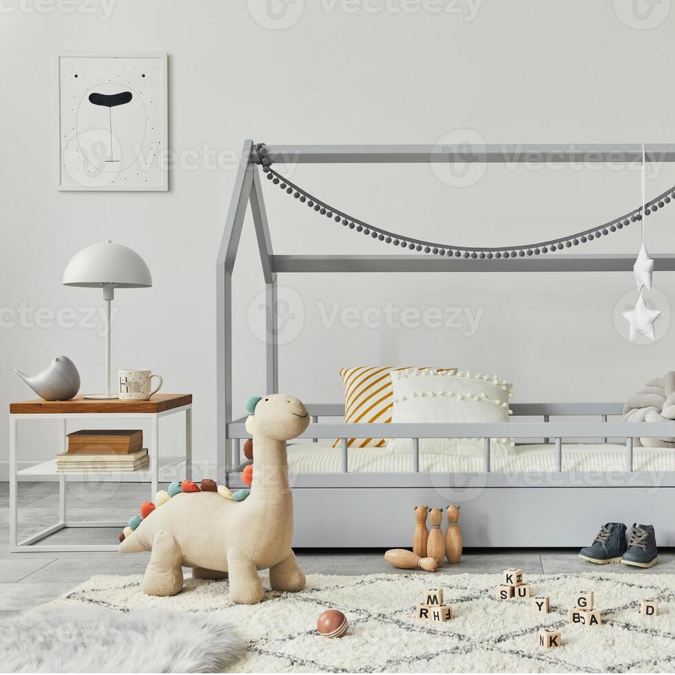 Stylish scandinavian child's room with creative wooden bed, coffee table, lamp, wooden shelf, plush and wooden toys and hanging textile decorations. Grey walls, carpet on the floor. Template. photo