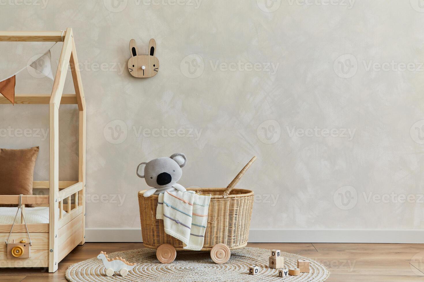 Stylish composition of cozy scandinavian child's room interior with bed, rattan basket, plush and wooden toys and textile hanging decorations. Creative wall, carpet on the floor. Copy space. Template. photo