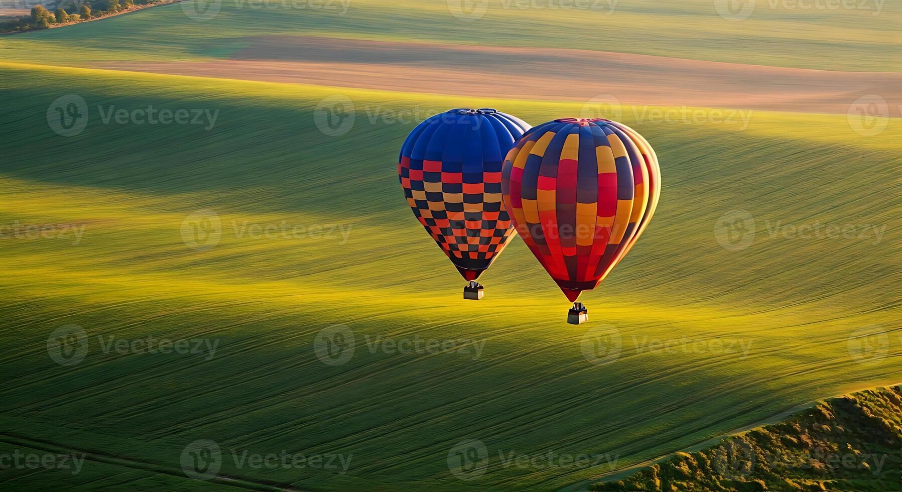 Two hot air balloons flying over a green field photo