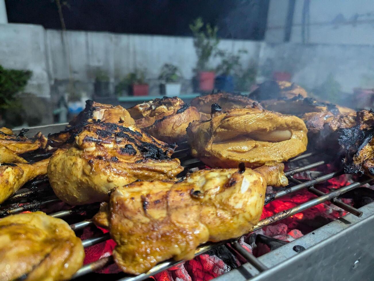 Grilling juicy chicken pieces over glowing charcoal in a cozy backyard during a warm evening gathering with friends and family enjoying delicious food and lively conversations photo