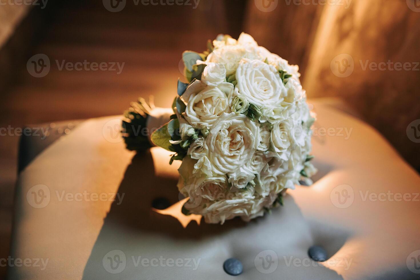 A bouquet of white flowers sits on a chair. The flowers are arranged in a way that they look like they are in a vase. The arrangement is simple and elegant, with the white flowers being the main focus photo