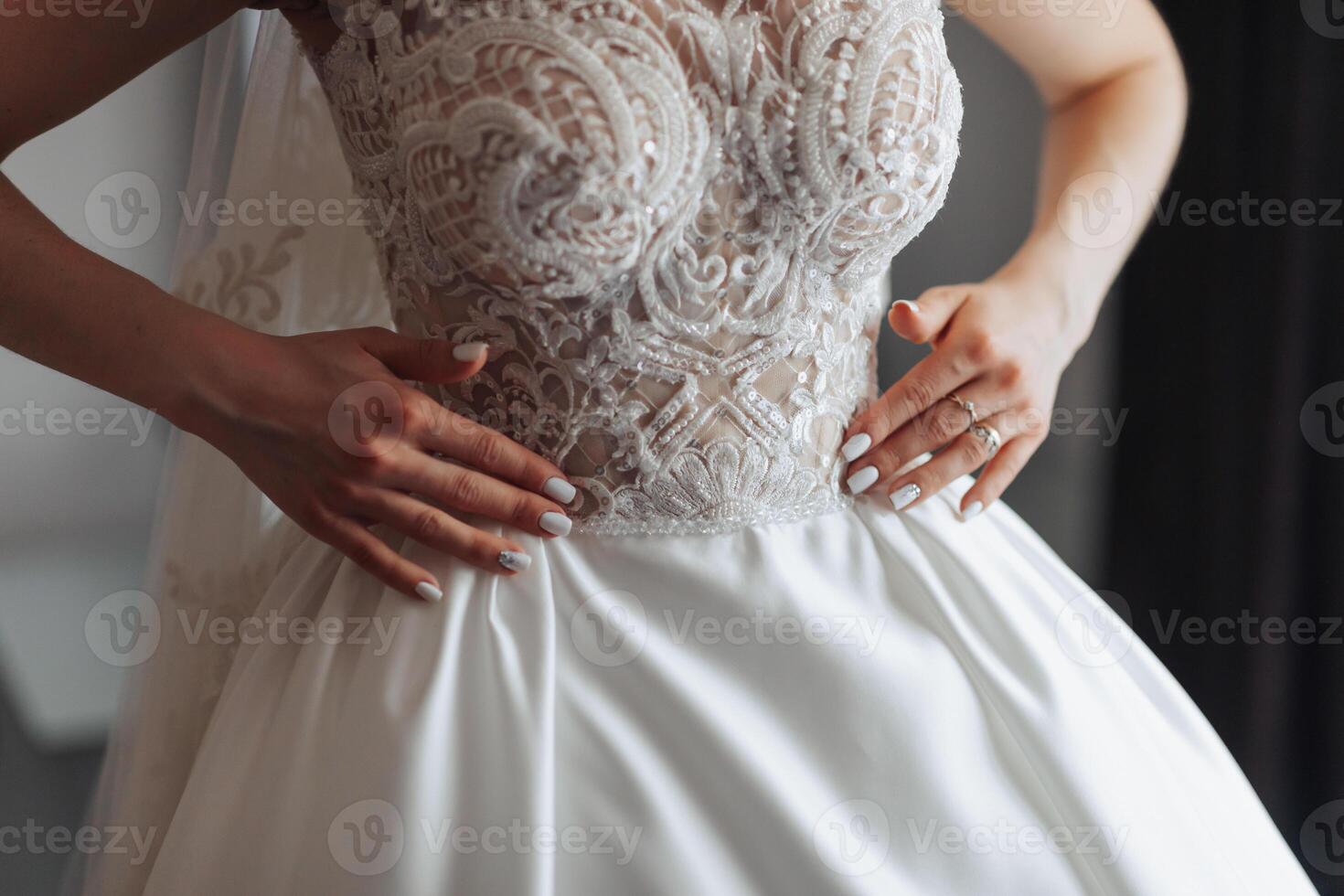 A woman in a white dress with a lace collar and a white band on her finger. She is holding her hands together photo