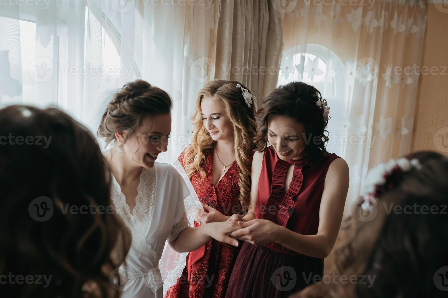 A group of women are standing together, one of them wearing a red dress photo