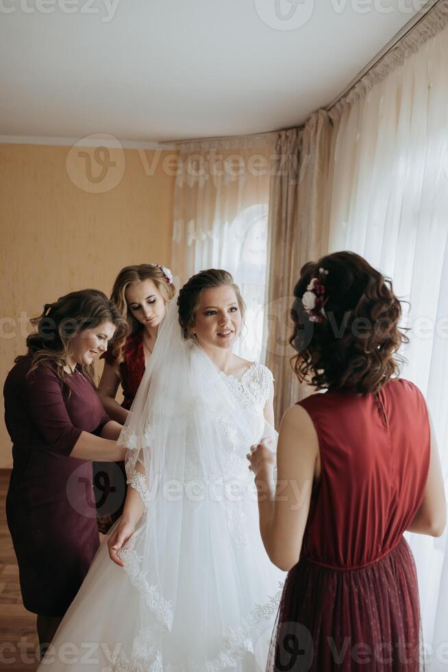 A bride is getting ready for her wedding with her bridesmaids photo