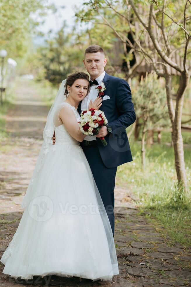 A bride and groom are posing for a picture in front of a tree photo