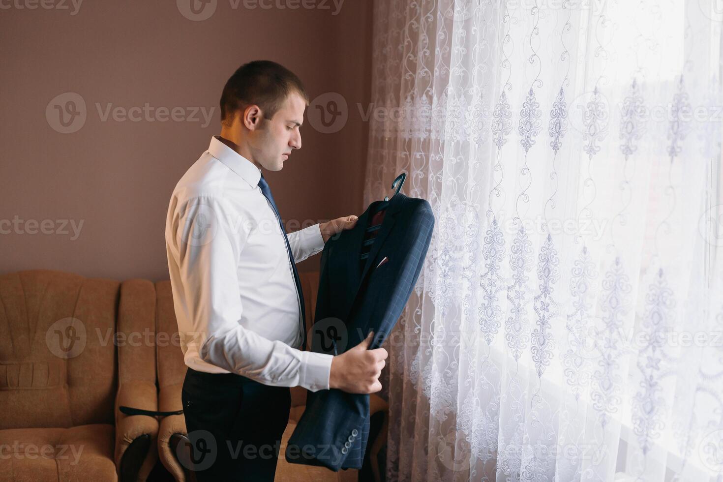 A man in a suit is hanging his jacket on a window photo
