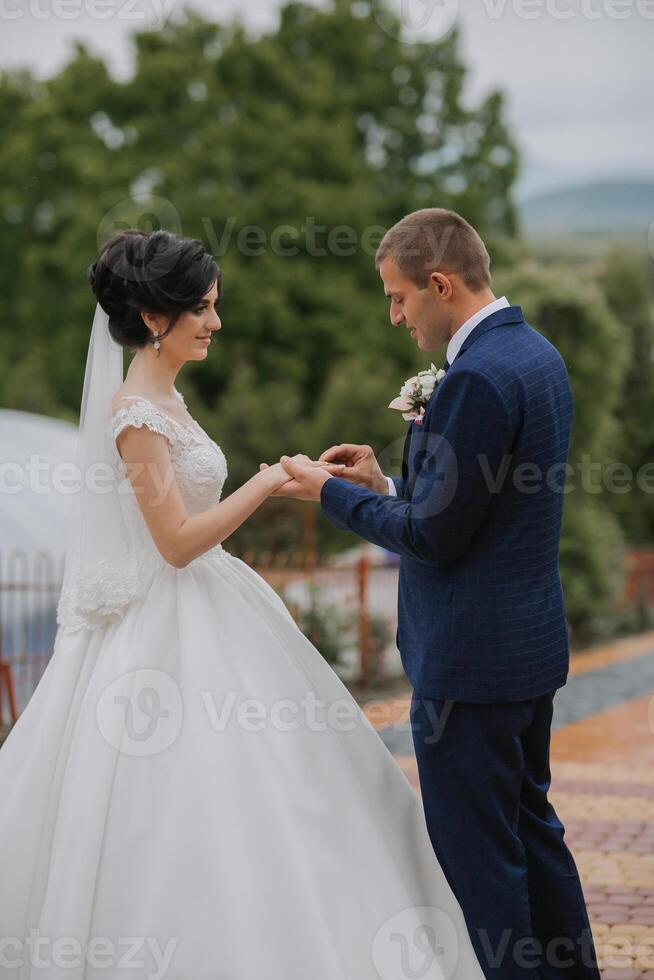 A bride and groom are getting married and the bride is wearing a white dress photo