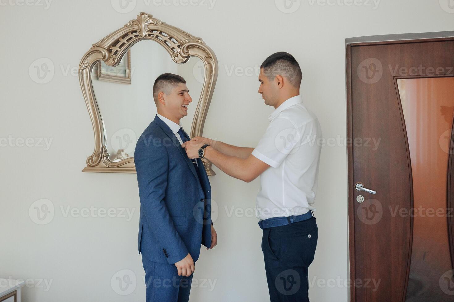 A man in a suit is getting his tie adjusted by another man photo