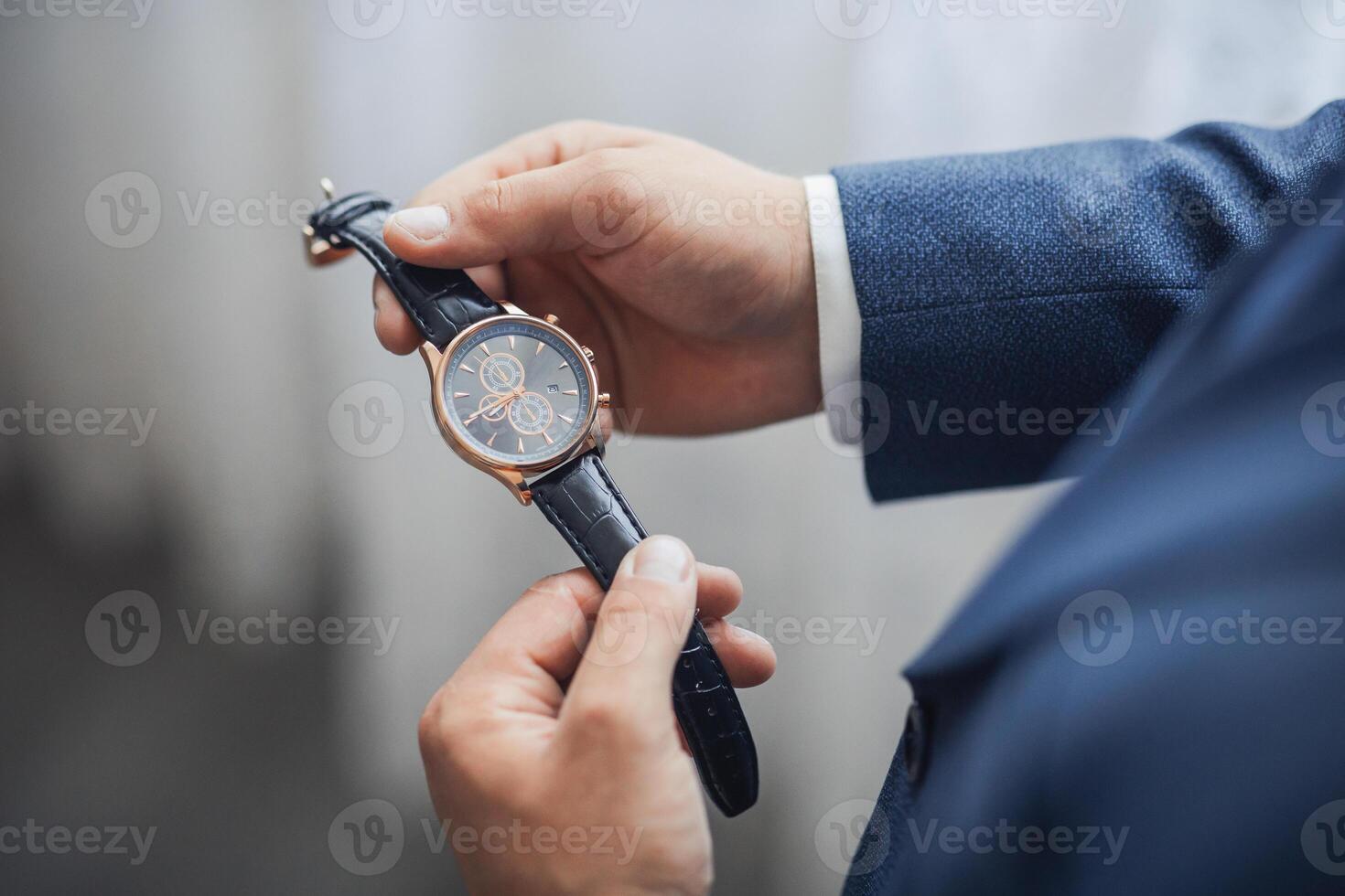 A man is wearing a watch and holding it up to his face photo
