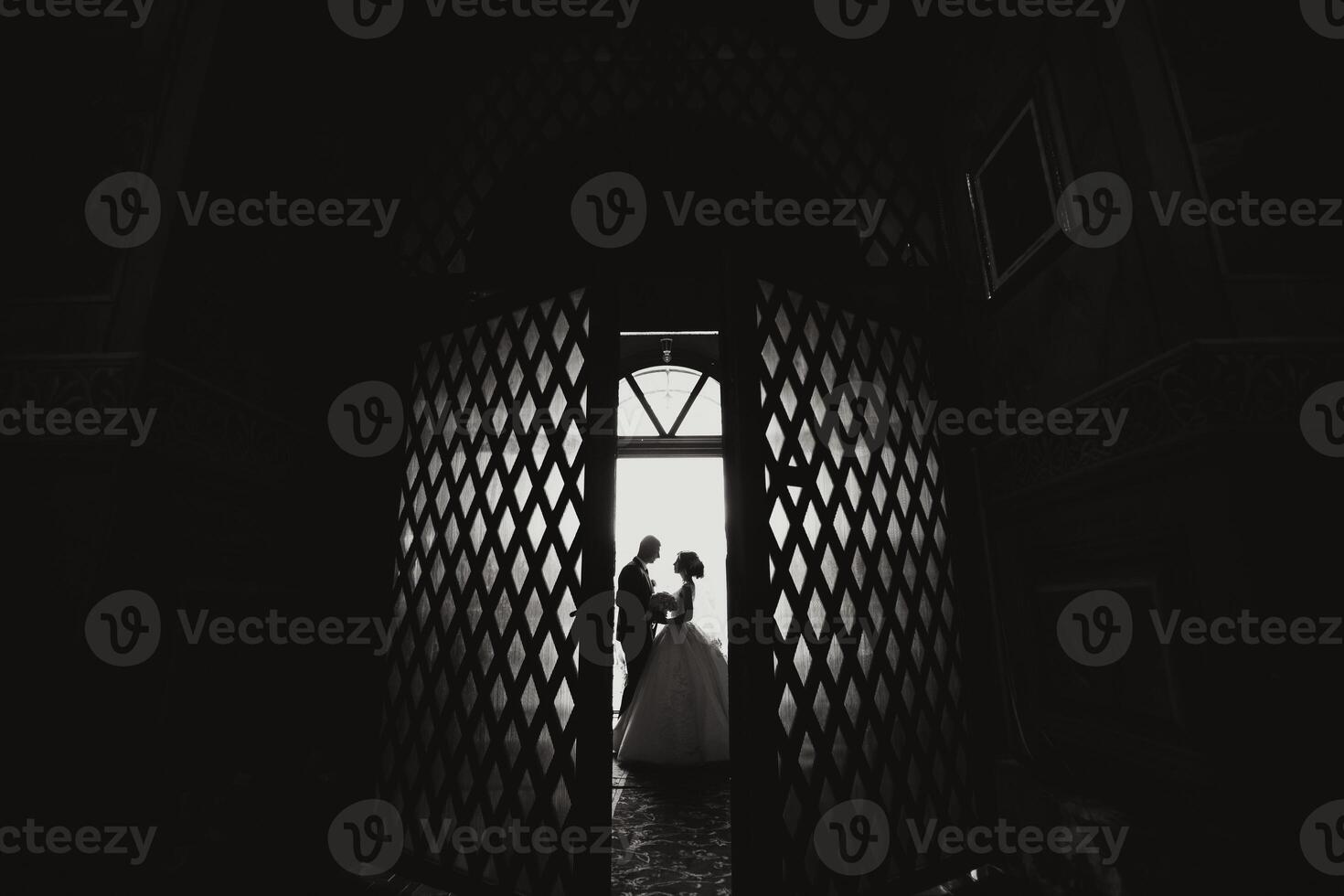 A bride and groom are standing in front of a doorway photo