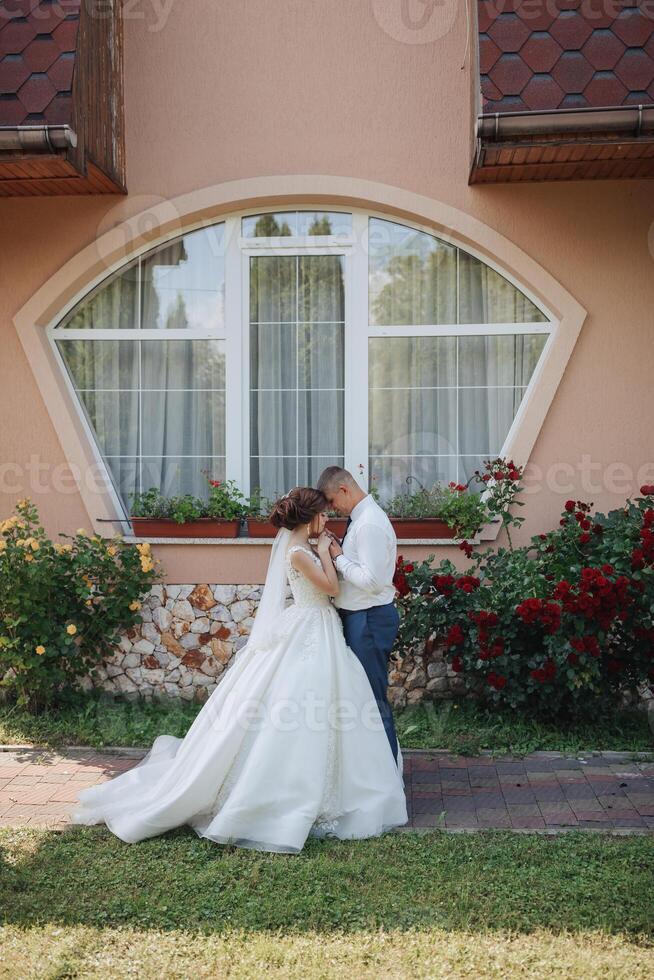 A bride and groom are standing in front of a building with a window photo