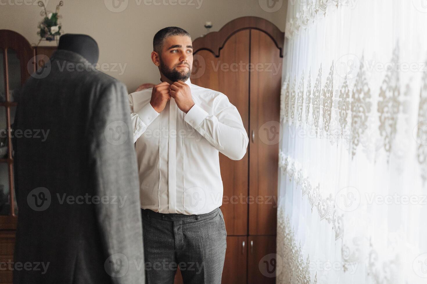 A man is getting dressed in front of a mannequin photo