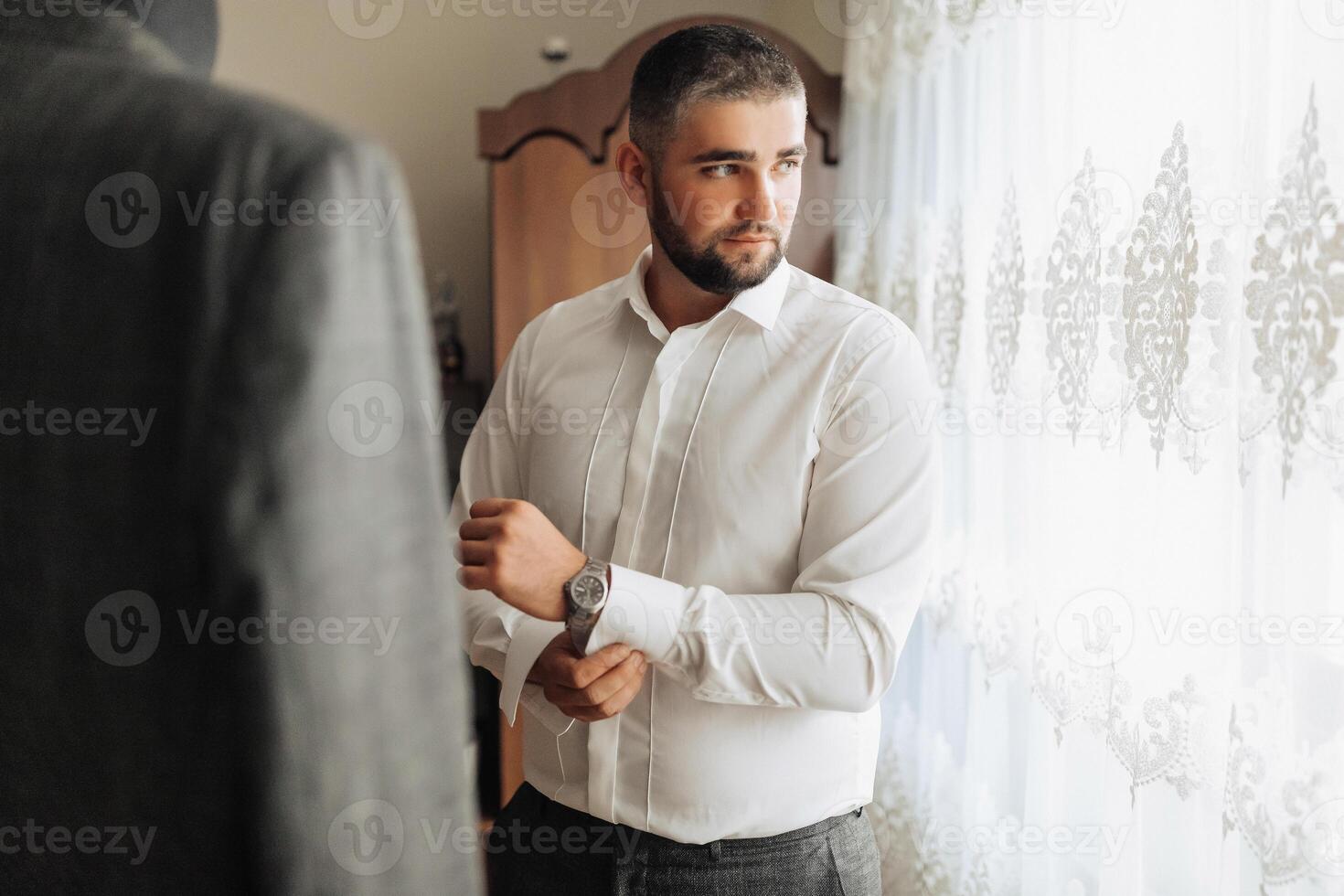 A man in a suit is getting ready to leave and is adjusting his watch photo