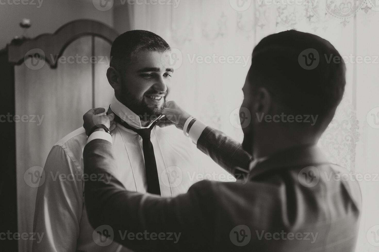 A man is getting dressed and his friend is helping him photo